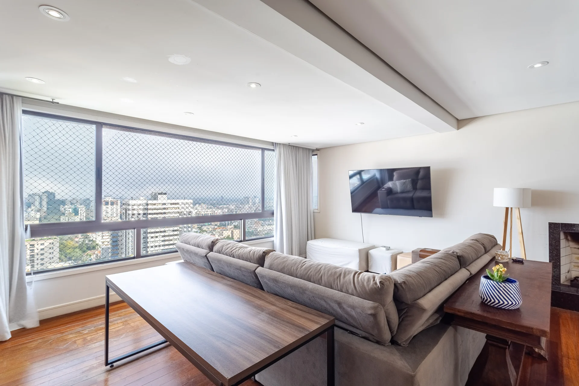 Sala de outro apartamento da mesma carteira, com mesa de jantar e janela panorâmica voltada para o bairro